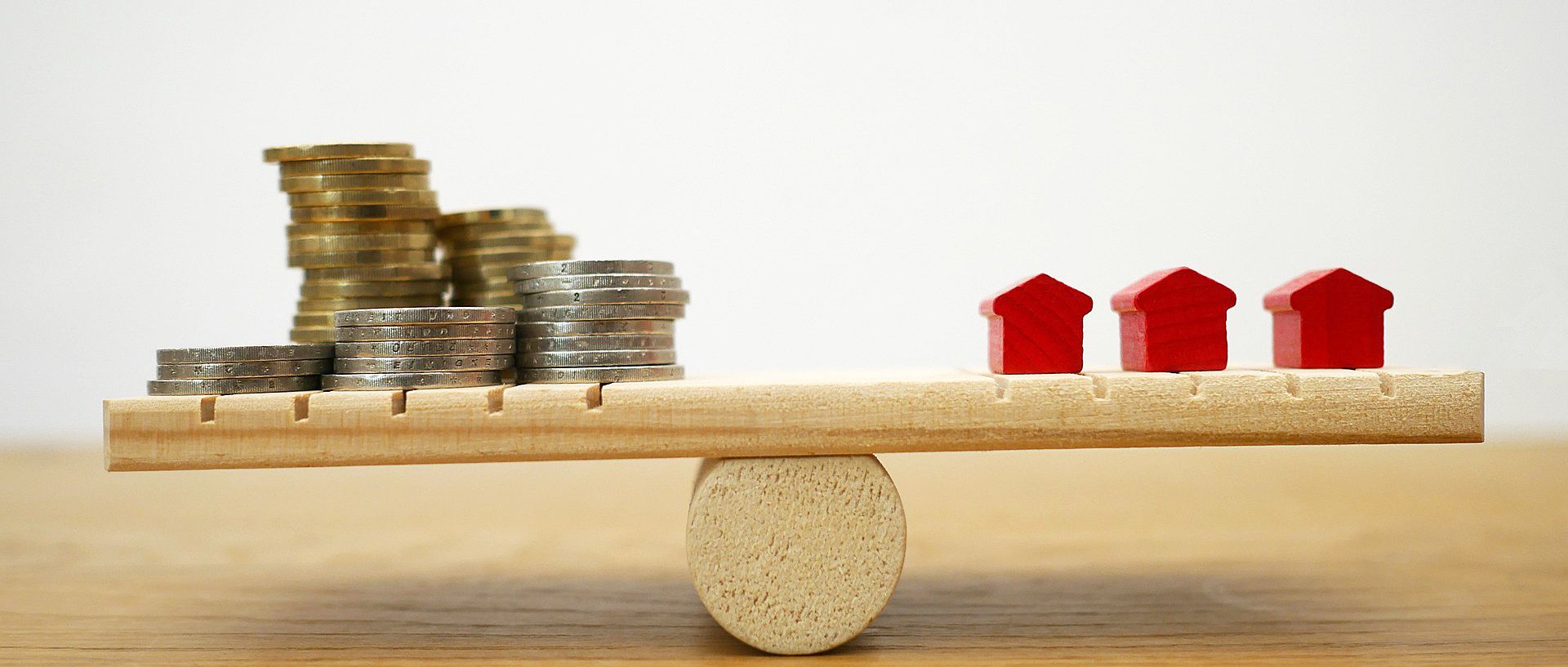 Symbolbild Waage mit Münzstapel und Häuser