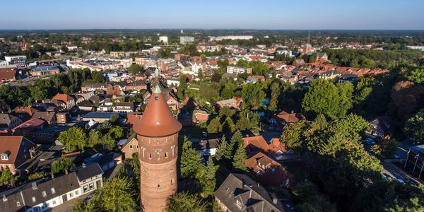 Luftaufnahme von Bad Segeberg mit dem Wasserturm im Vordergrund, umgeben von Wohnhäusern, viel Grün und der Innenstadt im Hintergrund