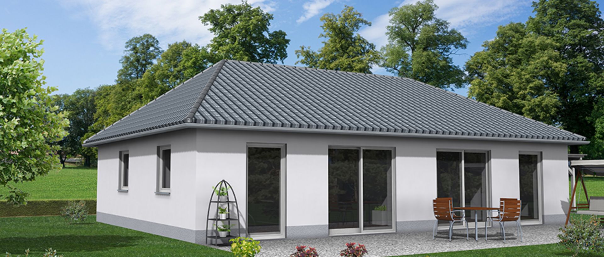 Einstöckiges Einfamilienhaus mit weißer Fassade und dunklem Walmdach. Auf der Rückseite befinden sich große bodentiefe Fenster und eine Terrasse mit Tisch und vier Stühlen. Das Haus steht auf einem gepflegten grünen Rasen und ist von Bäumen umgeben.