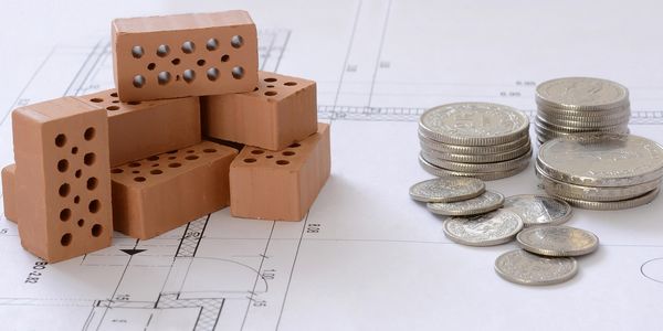 Symbolbild Backsteine und Euromünzen