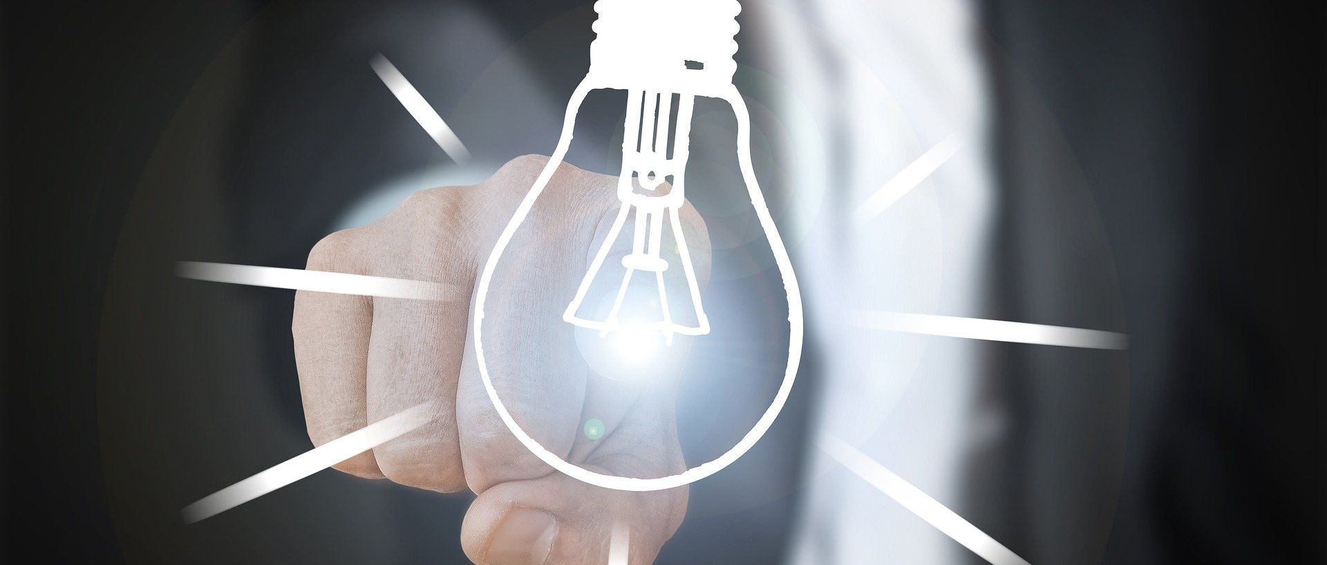 Ein Mann in Anzug tippt mit dem Finger auf eine leuchtende, digital dargestellte Glühbirne.